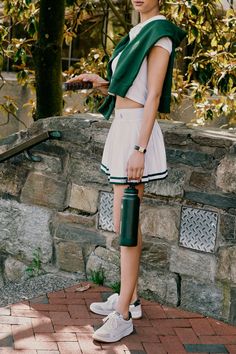 a woman in white and green outfit holding an umbrella