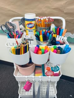 a white cart with lots of pens, pencils and markers on top of it