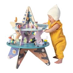 a small child playing with a wooden toy carousel set up in the shape of a star