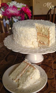 a white cake sitting on top of a table next to a plate with a slice taken out of it