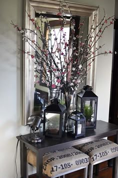 a table with vases and candles on it in front of a mirror next to a window