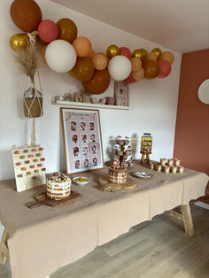 a table topped with lots of desserts and balloons hanging from the wall above it