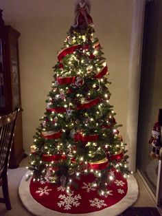 a decorated christmas tree with red and white ribbon