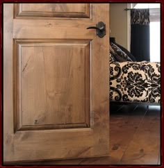 an open wooden door with a black and white pillow on the floor in front of it