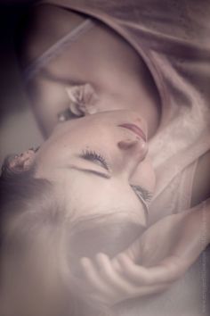 a woman laying in bed with her eyes closed next to a baby's head