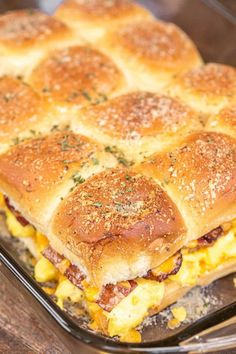 a sandwich with cheese and meat on it in a glass baking dish sitting on a wooden table