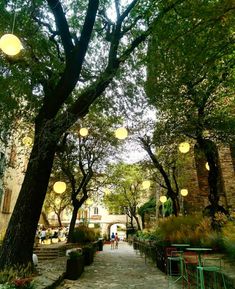 the walkway is lined with tables and chairs under hanging lights in an alleyway between two buildings