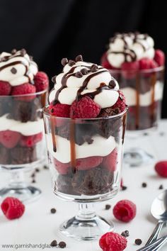 two desserts with raspberries, chocolate and whipped cream in them on a table