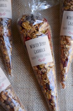 three bags of granola sitting next to each other on top of a cloth covered table