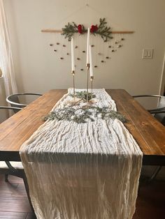 a wooden table topped with a white cloth covered tablecloth and two candles on top of it