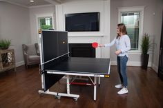 a woman is playing ping pong in the living room