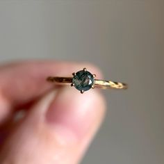 a close up of a person holding a gold ring with a blue diamond in it