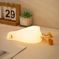 a white light sitting on top of a table next to a calendar and a plant