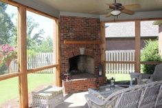 a screened porch with wicker furniture and a brick fireplace