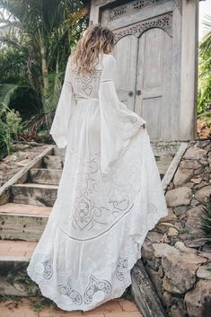 a woman in a white dress is walking up some steps and looking at the door