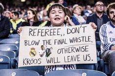 a young boy holding up a sign at a soccer game with other people sitting in the bleachers