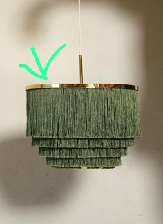 a green chandelier hanging from the ceiling with an arrow pointing up at it