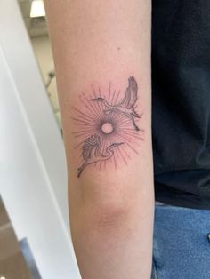 a woman's arm with a tattoo on it that has two birds flying in the sky