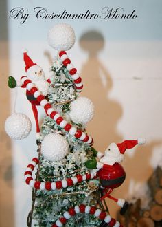 a small christmas tree with santa clause decorations on it's top and white balls around the base