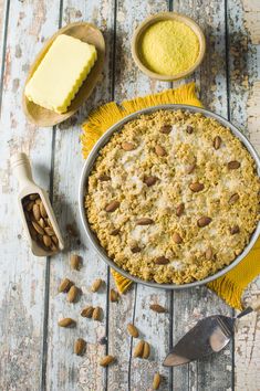 a pie sitting on top of a wooden table next to two bowls filled with nuts