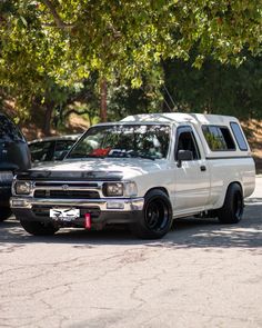 a white pick up truck parked in a parking lot next to other cars and trees