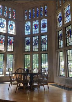 a dining room with stained glass windows and wooden table surrounded by chairs in front of them