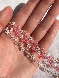 a hand holding some tiny white and pink flowers