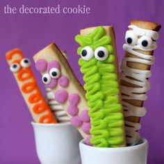 four decorated cookie sticks in a cup with googly eyes