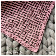 a pink crocheted blanket laying on top of some rocks