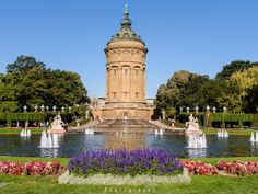 there is a fountain in the middle of this park with many flowers and trees around it