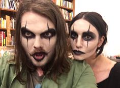 two people with makeup on their faces are posing for a photo in front of bookshelves