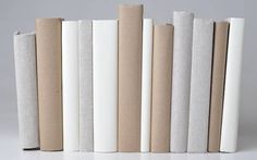 several white and beige books lined up on top of each other in front of a gray background