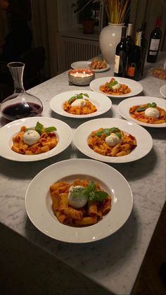 several plates of food on a table with wine and bottles in the backround