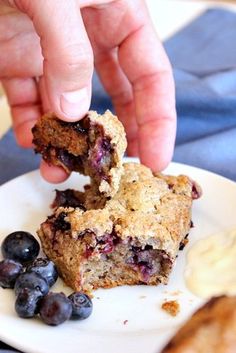 a person picking up some blueberry muffins on a plate