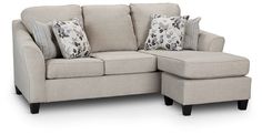 a sectional couch with pillows on it and a footstool next to it,