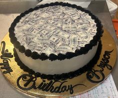 a birthday cake with money on it sitting on top of a table next to scissors