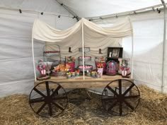 a wagon filled with candy and candies on top of dry grass under a tent