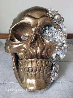 a gold skull with pearls and jewels on it's head sits on a tile floor