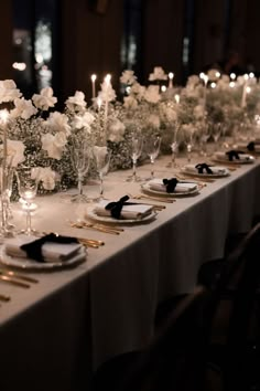 a long table is set with white flowers and candles for an elegant dinnereon party