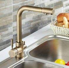 a kitchen sink with a bowl of fruit and bread on the counter