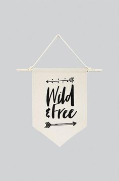 a white banner that says wild and free with an arrow hanging on the wall above it