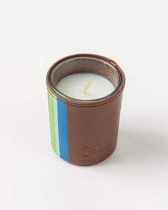 a candle that is sitting on top of a white surface with a rainbow stripe around it