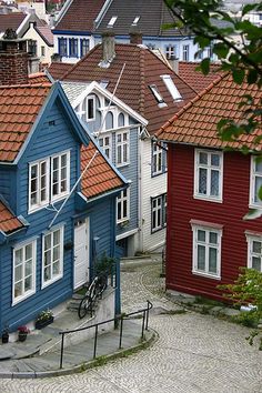 a cobblestone street with many colorful houses on the side and one bicycle parked in front