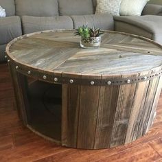 a round wooden table sitting on top of a hard wood floor next to a couch