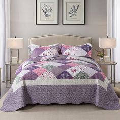 a bed covered in a purple quilt next to two framed pictures