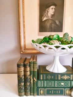 a white bowl filled with green eggs sitting on top of books