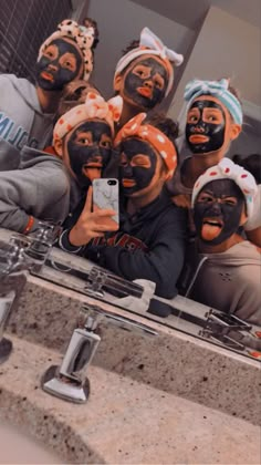 a group of people with face paint on taking a selfie in front of a mirror