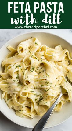 a white bowl filled with pasta and garnished with dill