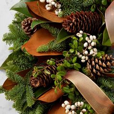 a wreath with pine cones, berries and greenery