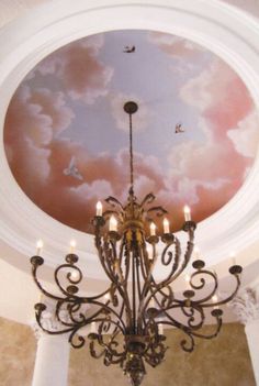 a chandelier hanging from the ceiling in front of a painting on the ceiling